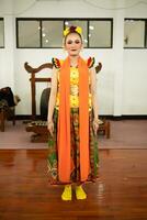 une traditionnel indonésien Danseur permanent dans une Jaune costume et un Orange écharpe pendaison vers le bas sa corps photo