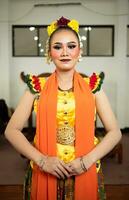 une traditionnel indonésien Danseur permanent dans une Jaune costume et un Orange écharpe pendaison vers le bas sa corps photo