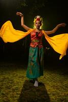 une traditionnel indonésien Danseur danses avec une Jaune écharpe cette flotteurs dans le air photo