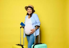 souriant Enceinte femme touche sa ventre, voyages à l'étranger pour été va-t-en ou accouchement, isolé sur Jaune Contexte photo