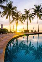 Parapluie et chaise autour de la piscine de l'hôtel resort avec lever de soleil le matin