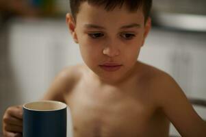 visage portrait de un adorable garçon avec une céramique tasse avec chaud boisson photo