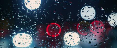 conduite dans il pleut. pluie sur voiture pare-brise ou voiture fenêtre dans pluvieux saison et floue circulation route dans Contexte. pluie gouttes sur voiture miroir. route dans pluie. bruine il pleut diminue conduite visibilité. photo