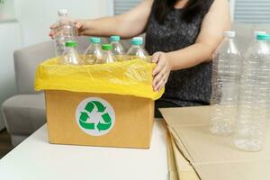 Accueil recycler éco vert zéro concept femme lancement vide Plastique bouteille dans recyclage poubelle avec Jaune des ordures Sacs à maison. photo