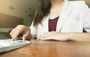 affaires femme en cours d'analyse investissement graphiques avec calculatrice portable. comptabilité et La technologie dans bureau.business gens en utilisant portable à Bureau analyser plans.sélectif concentrer photo