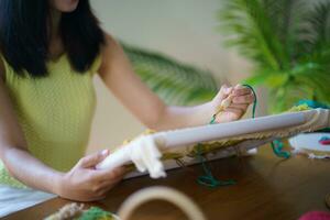 coup de poing aiguille. asiatique femme fabrication Fait main loisir tricot dans studio atelier. designer lieu de travail Fait main artisanat projet DIY broderie concept. photo