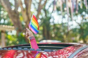 content asiatique femme soutien lgbt fierté parade dans auto. avec arc en ciel de lgbtq ou lgbtqia. photo