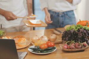 Beau homme séance près le sien épouse à cuisine. famille couple voir social médias, le surf le la toile tandis que séance à cuisine table avec générique portable. couple travail avec portable à Accueil photo