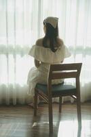 silhouette de femme séance sur le lit à côté de le les fenêtres avec lumière du soleil dans le Matin photo