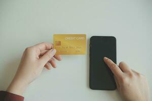 mains de femme tenant et utilisant une carte de crédit pour faire des achats en ligne. photo