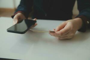 mains de femme tenant et utilisant une carte de crédit pour faire des achats en ligne. photo