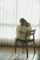 silhouette de femme séance sur le lit à côté de le les fenêtres avec lumière du soleil dans le Matin photo