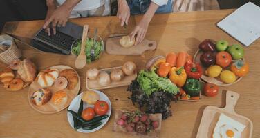 Beau homme séance près le sien épouse à cuisine. famille couple voir social médias, le surf le la toile tandis que séance à cuisine table avec générique portable. couple travail avec portable à Accueil photo