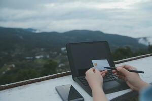 en ligne paiement, Jeune femme en portant crédit carte et dactylographie sur portable photo