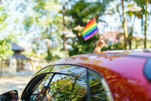 content asiatique femme soutien lgbt fierté parade dans auto. avec arc en ciel de lgbtq ou lgbtqia. photo