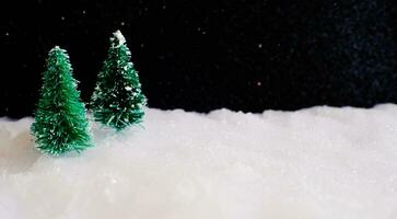 Noël Accueil décoration avec peu Fait main cadeau boîte dans une neige couvert miniature à feuilles persistantes forêt et bokeh lumière pour copie espace. photo