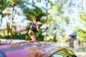 content asiatique femme soutien lgbt fierté parade dans auto. avec arc en ciel de lgbtq ou lgbtqia. photo