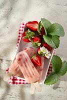 une assiette avec deux sucettes glacées sur il et des fraises photo