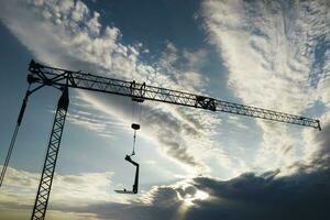 le profil de une construction grue à le coucher du soleil photo