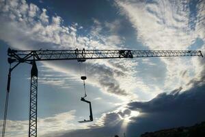 le profil de une construction grue à le coucher du soleil photo