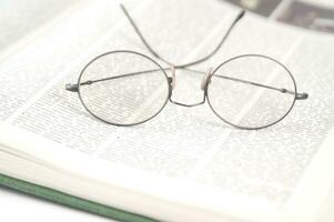 une paire de des lunettes est séance sur Haut de un ouvert livre photo