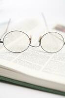 une paire de des lunettes est séance sur Haut de un ouvert livre photo