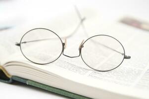 une paire de des lunettes est séance sur Haut de un ouvert livre photo