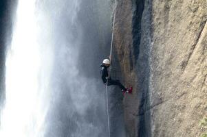 une la personne sur une corde escalade en haut une cascade photo