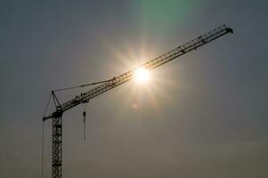 une grue est silhouette contre le Soleil photo