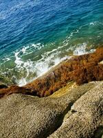 une rocheux rive avec vagues s'écraser contre le rochers photo