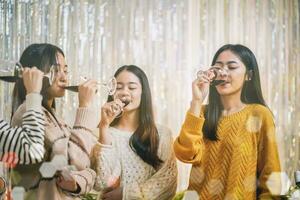 de bonne humeur copains profiter Accueil anniversaire vacances faire la fête. asiatique copains applaudissement en buvant rouge du vin célébrer Nouveau année faire la fête. photo