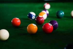 homme main et queue bras en jouant billard Jeu ou en train de préparer visée à tirer bassin des balles sur une vert billard tableau. coloré billard des balles sur vert frise. photo