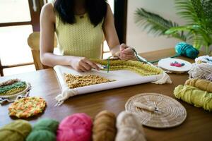 coup de poing aiguille. asiatique femme fabrication Fait main loisir tricot dans studio atelier. designer lieu de travail Fait main artisanat projet DIY broderie concept. photo