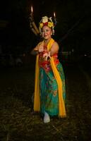 une traditionnel Javanais Danseur danses avec coloré fleurs sur sa poing tandis que sur étape photo