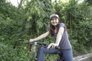 indonésien femme cyclisme autour le parc dans le Matin. photo