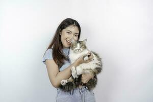 portrait de Jeune asiatique femme en portant mignonne angora chat avec Jaune yeux. femelle étreindre sa mignonne longue cheveux minou isolé par blanc Contexte. adorable national animal de compagnie concept. photo