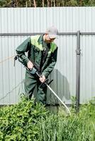 une homme tond pelouse herbe avec une pelouse tondeuse. essence pelouse tondeuse, tondeuse fermer. homme travail dans le jardin photo