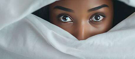 africain fille cache visage en dessous de couverture tandis que mensonge dans lit photo