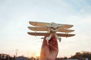 liberté concept, Humain main en portant en bois avion sur le le coucher du soleil ciel Contexte photo