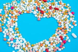 beaucoup pilules dans le forme de une cœur multicolore sur une bleu Contexte photo