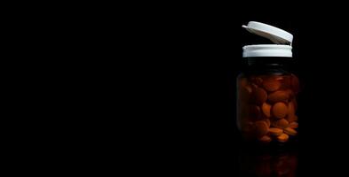 le pilules sont dans le Orange médicament bouteille sur le noir Contexte photo