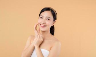 magnifique fille asiatique modèle émouvant Frais embrasé hydraté faciale peau sur beige Contexte fermer. beauté visage Jeune femme avec Naturel maquillage et en bonne santé peau portrait. peau se soucier concept photo