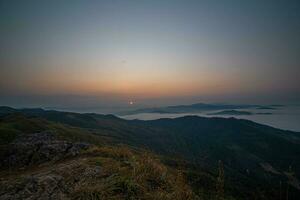 le étourdissant vue de une touristes point de vue comme elles ou ils aller vers le bas une colline sur une brumeux Piste avec une colline et une Contexte de une d'or ciel dans phu Langka forêt parc dans Phayao, Thaïlande. photo