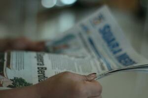 magelangindonesia-07312023-a Jeune indonésien fille est en train de lire une local journal dans une hôpital photo