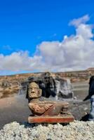 une statue de une homme séance sur une Roche dans le désert photo