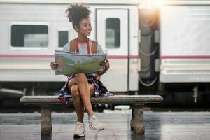 Jeune femme femelle souriant voyageur avec retour pack à la recherche à carte tandis que attendre pour le train à train gare. haute qualité photo