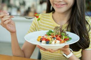 régime et suivre un régime, prendre plaisir manger. en bonne santé femme tenir salade nourriture et sentiment heureux. beauté svelte femelle corps atteint poids perte objectif pour en bonne santé vie, fou à propos minceur, mince taille, nutritionniste. photo