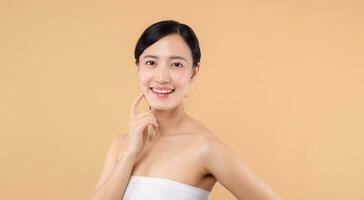 magnifique fille asiatique modèle émouvant Frais embrasé hydraté faciale peau sur beige Contexte fermer. beauté visage Jeune femme avec Naturel maquillage et en bonne santé peau portrait. peau se soucier concept photo