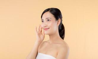 magnifique fille asiatique modèle émouvant Frais embrasé hydraté faciale peau sur beige Contexte fermer. beauté visage Jeune femme avec Naturel maquillage et en bonne santé peau portrait. peau se soucier concept photo