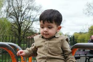 mignonne asiatique pakistanais bébé est profiter le magnifique ensoleillé journée à mise en garde les enfants et Publique parc de luton ville de Angleterre Royaume-Uni. faible angle image a été capturé sur avril 03ème, 2023 photo